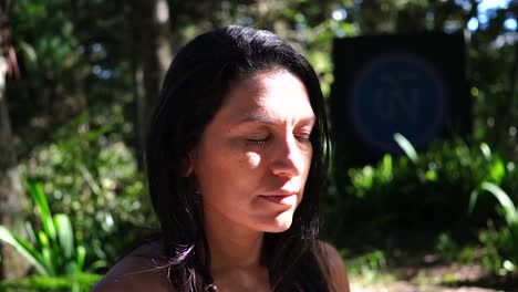 A-woman-practising-meditation-with-her-face-bathing-in-the-sun-in-a-green-environment