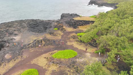 group of people walking to the pont naturel on a cliff of volcanic rocks in mauritius