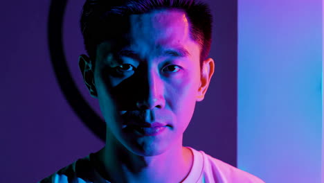 close-up portrait of a man under dramatic blue and purple neon lights