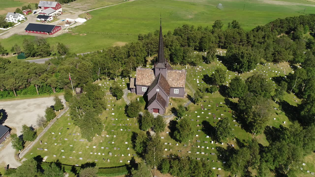 전통적인 목조 교회와 묘지의 클로즈업 드론, 시골 지역의 초록색 속에 자리잡고 있습니다.