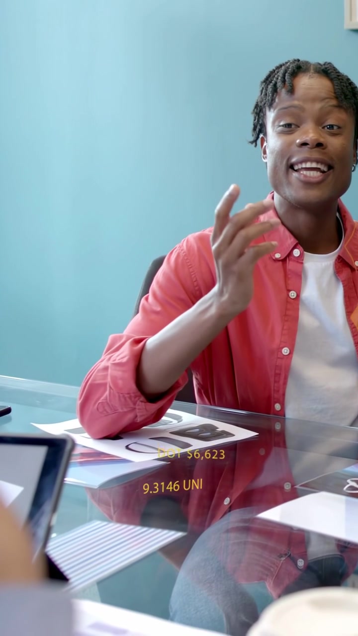 Vertical video: Man in red shirt explaining crypto trends as AR tickers update over glass table