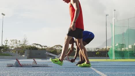 dos atletas preparándose para una carrera en el estadio