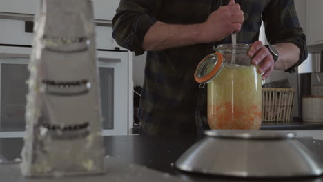 caucasian male preparing homemade kombucha, fermented drink, tracking shot, slow motion