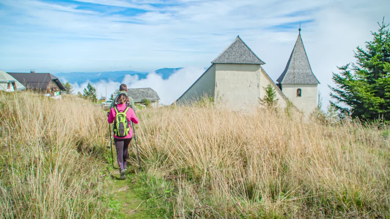 Hikers on a path near a church in the mountains