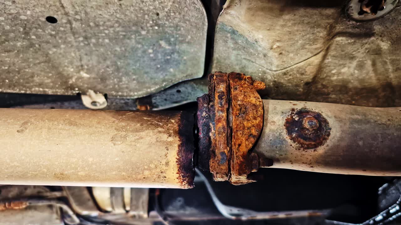Undercarriage of vehicle with visible rusted snapped broken axle and suspension system, maintenance inspection view