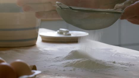 hands of man sifting flour on kitchen table before baking