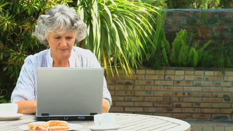 Retired-woman-using-a-laptop-outdoors