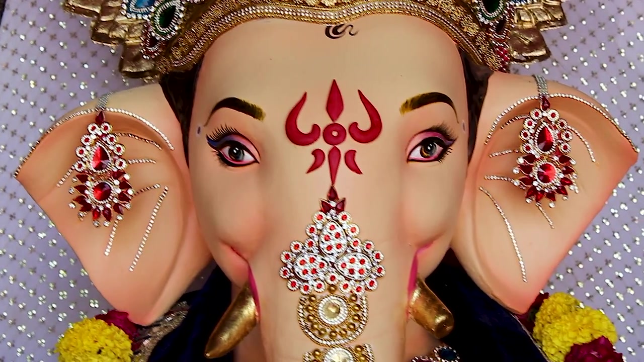 Macro primo piano del volto di un idolo di Ganesha che mostra occhi, tilak e orecchini durante il festival di Ganesh Chaturthi a Mumbai, India