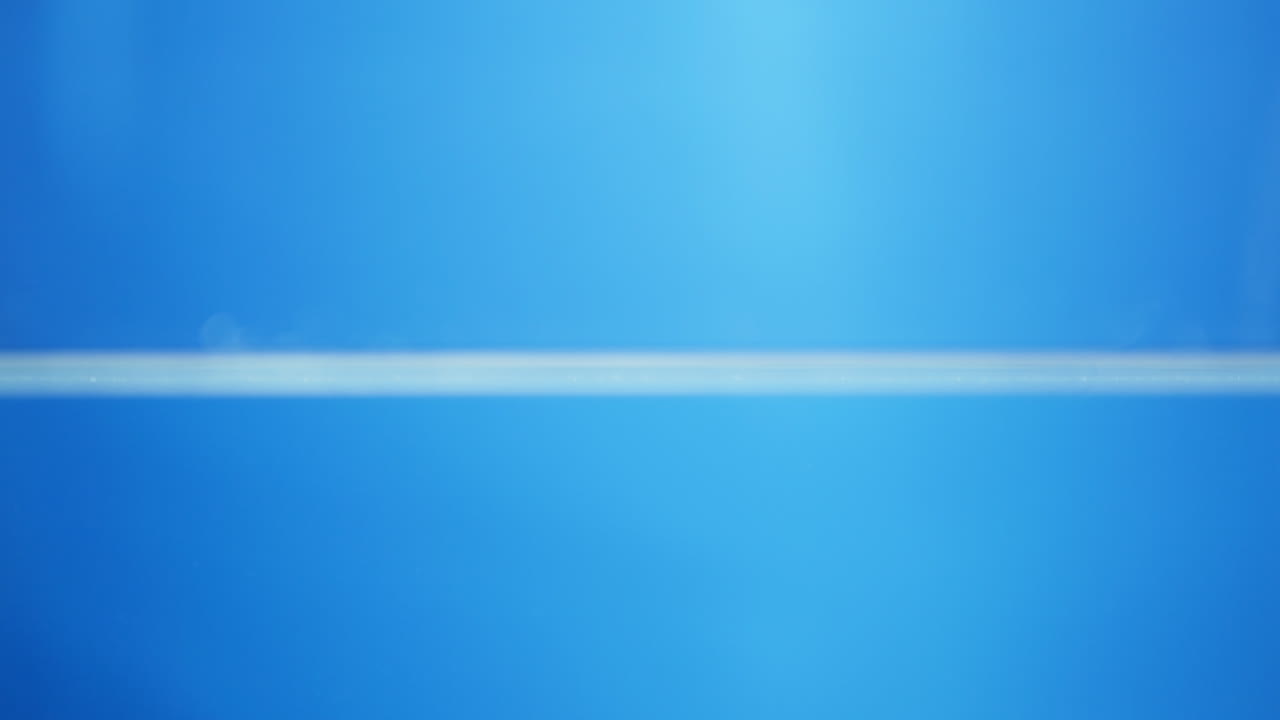 Slow-motion water drop hits a reflective surface, rippling outward with perfect clarity and showing the essence of freshness and nature.