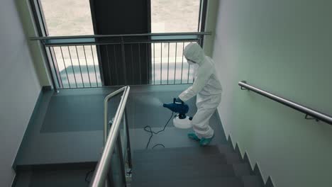 top view of person in protective suit disinfecting the staircase