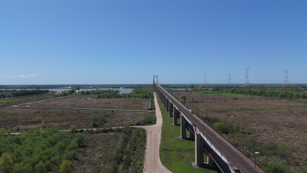 Capturing the expansive aerial view of justo jose de urquiza bridge stretching across the parana guazu river in argentina, surrounded by lush landscapes and vast waterways under a clear blue sky
