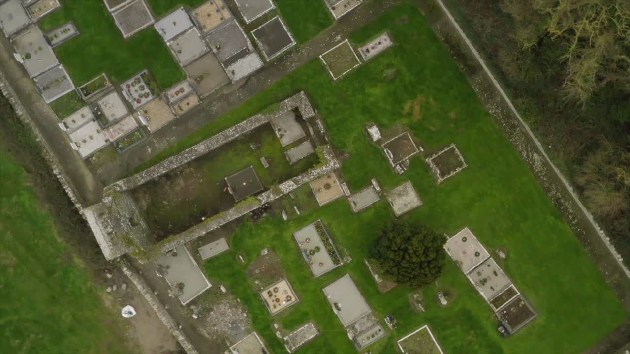 drone zenital vista de arriba hacia abajo gira sobre parcelas de cementerio y paredes de la iglesia vieja