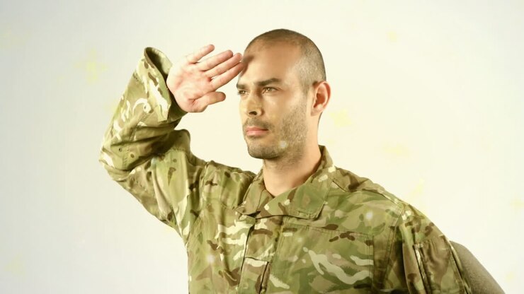 Saluting in camouflage uniform, person standing against plain background