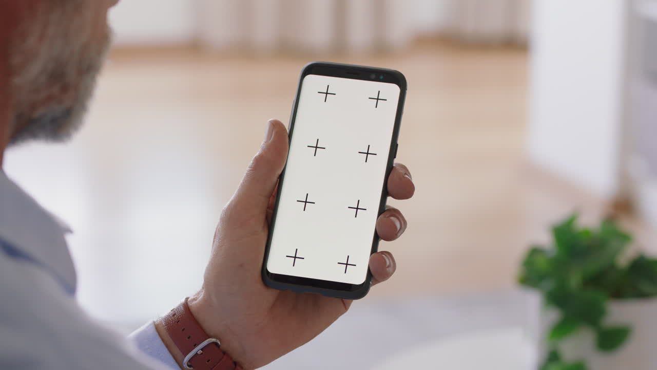 uomo maturo che usa uno smartphone che guarda lo schermo verde che guarda la chiave chroma che si gode l'intrattenimento online sul telefono cellulare