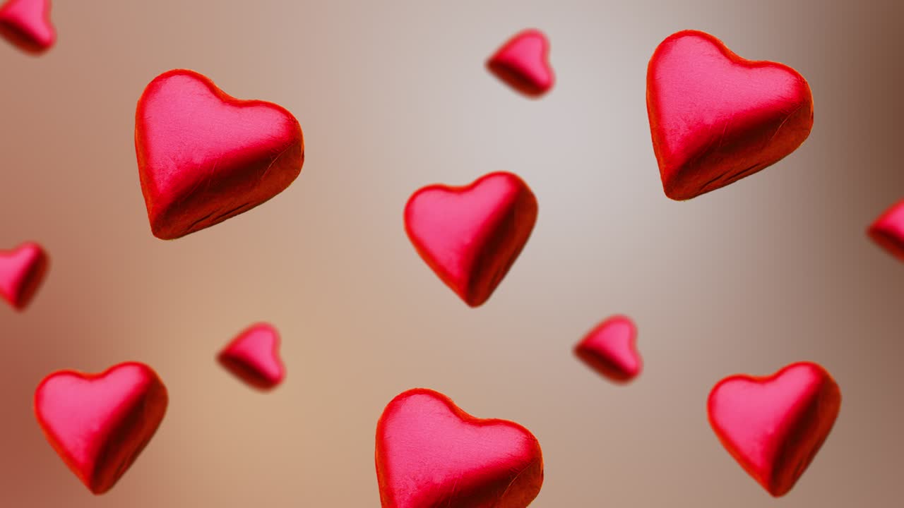 Cioccolatino incartato a forma di cuore che vola e ondeggia con diametri diversi su uno sfondo beige naturale. Concetto per San Valentino, matrimoni, compleanni e altre festività.