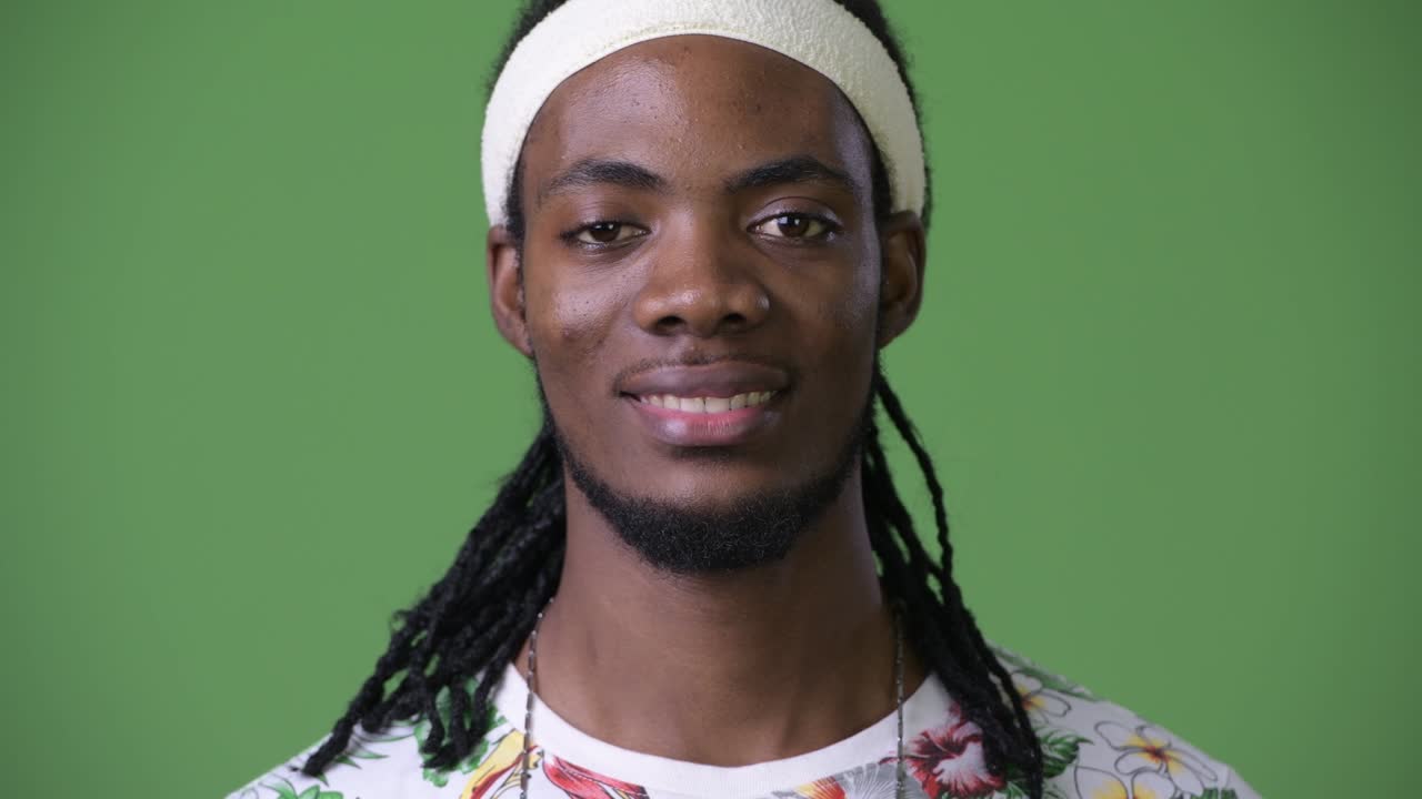 joven hombre africano guapo con dreadlocks contra un fondo verde