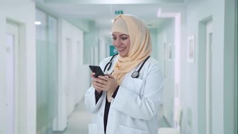 happy muslim doctor messaging someone on phone