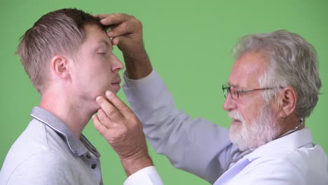 anciano barbudo médico consultando hombre paciente contra fondo verde