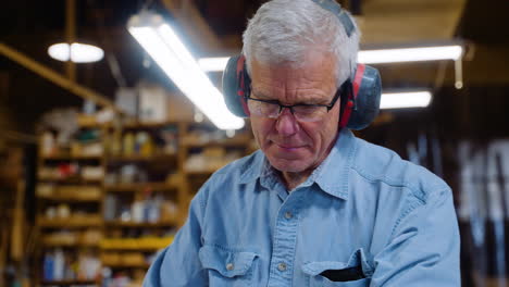 middle-aged woodworker planing wood with ear protection on