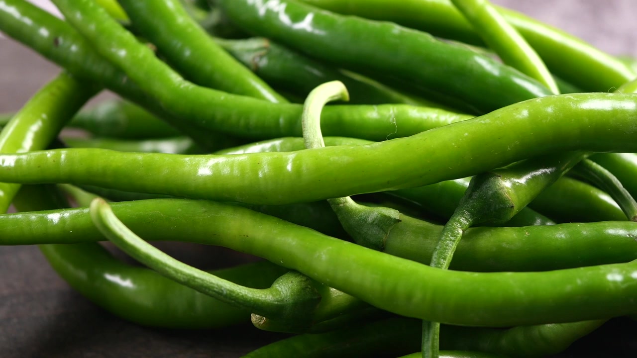 Close-up of Fresh Green Chili Peppers on a Wooden Surface