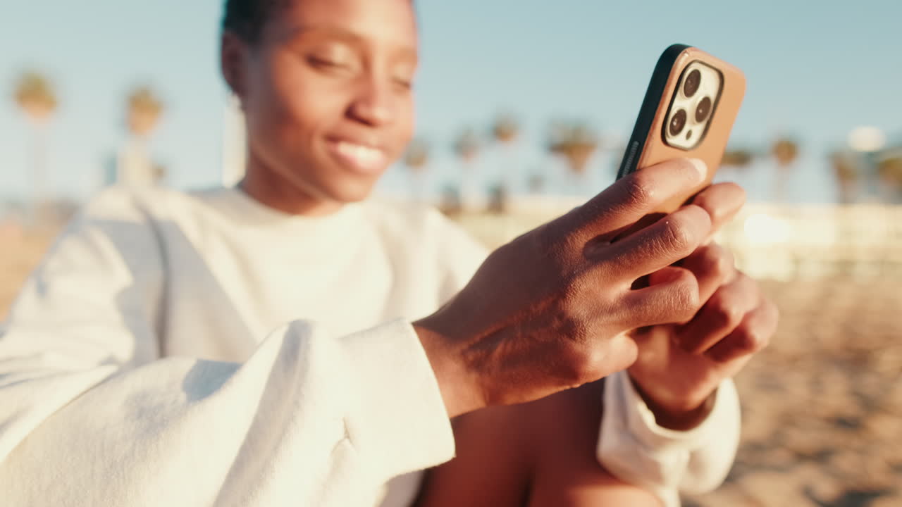 Joyeuse jeune femme afro-américaine utilisant un smartphone en plein air