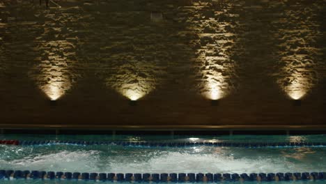 swimmers practicing in indoor pool at night