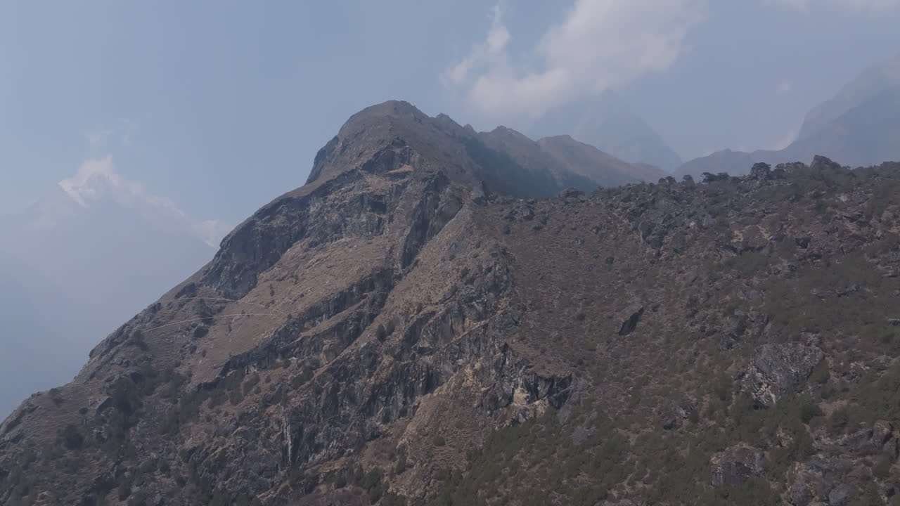 Mesmerising aerial shot of high-altitude trekking trail in Nepal with rocky paths, clouds, and dramatic hillside terrain capturing the struggle and beauty of adventure for Tourists and locals