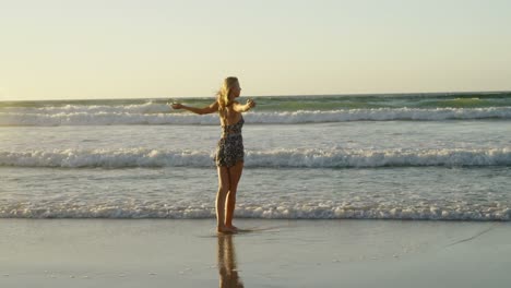 woman with arms outstretched playing in water at beach