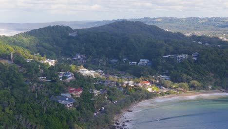aerial footage of byron bay's coastline and lush hills under soft daylight, captured with smooth drone movement