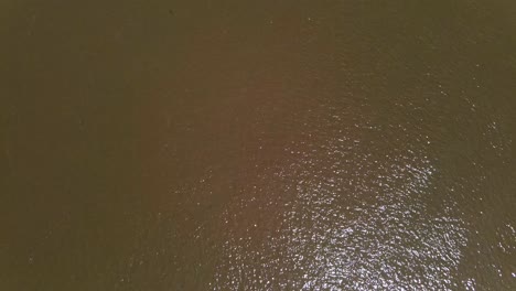 Drone-shot-of-dirty-river-water-with-sun-reflection