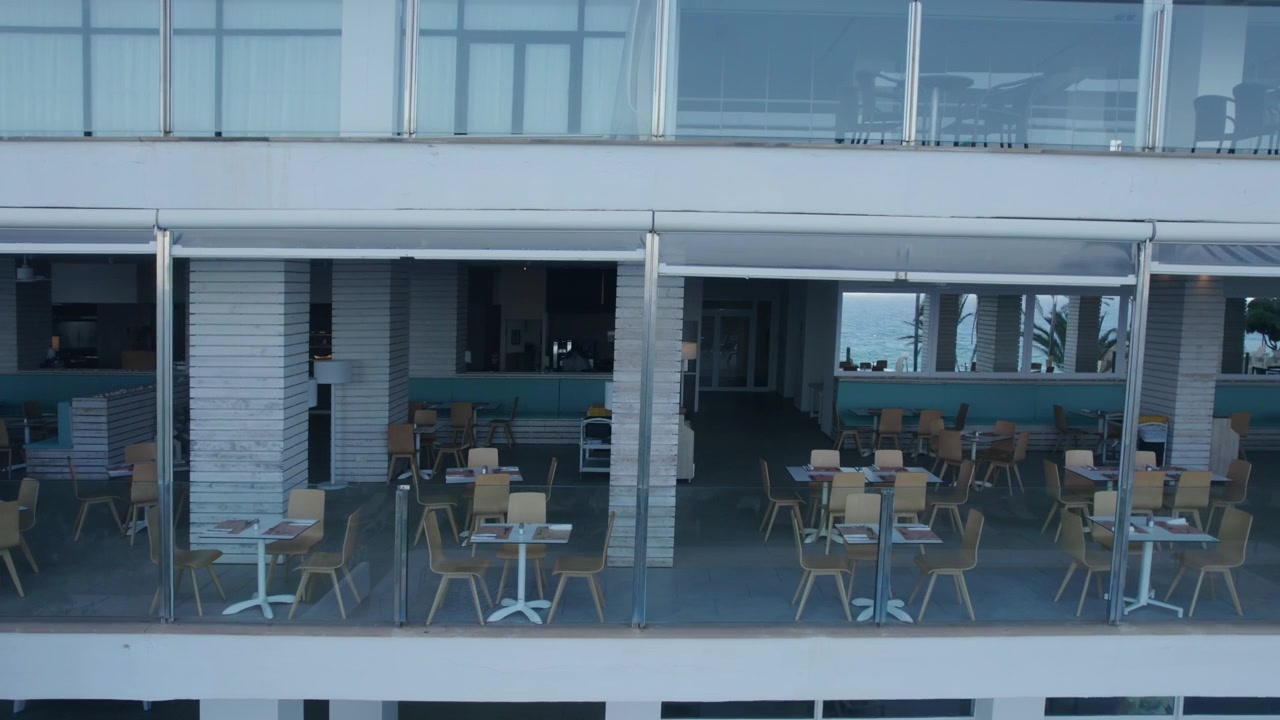 Sillas vacías en la terraza del área de comedor de un hotel resort costero en Mallorca, España.