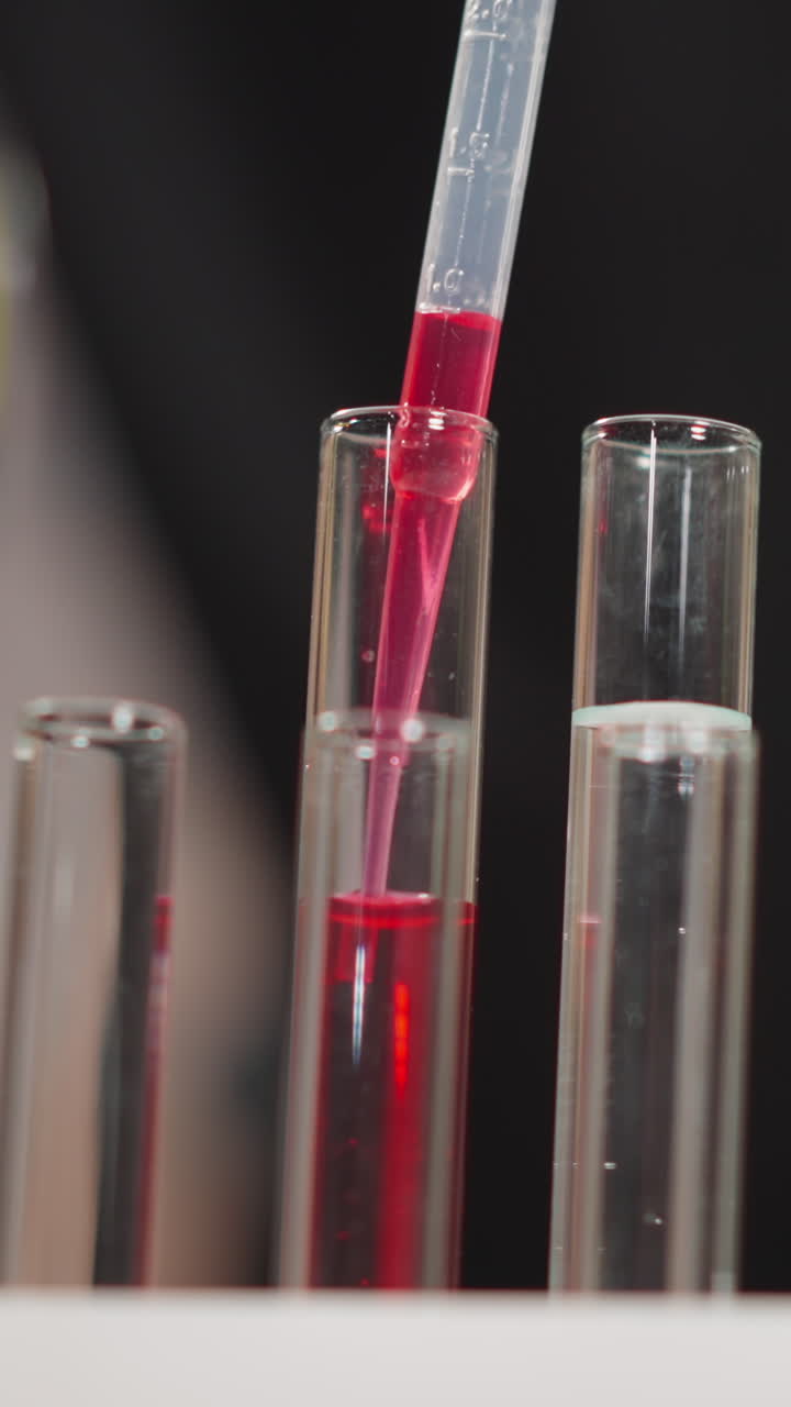 Taking bright pink liquid from glass tube with long plastic pipette for experiment in scientific chemical laboratory extreme close view