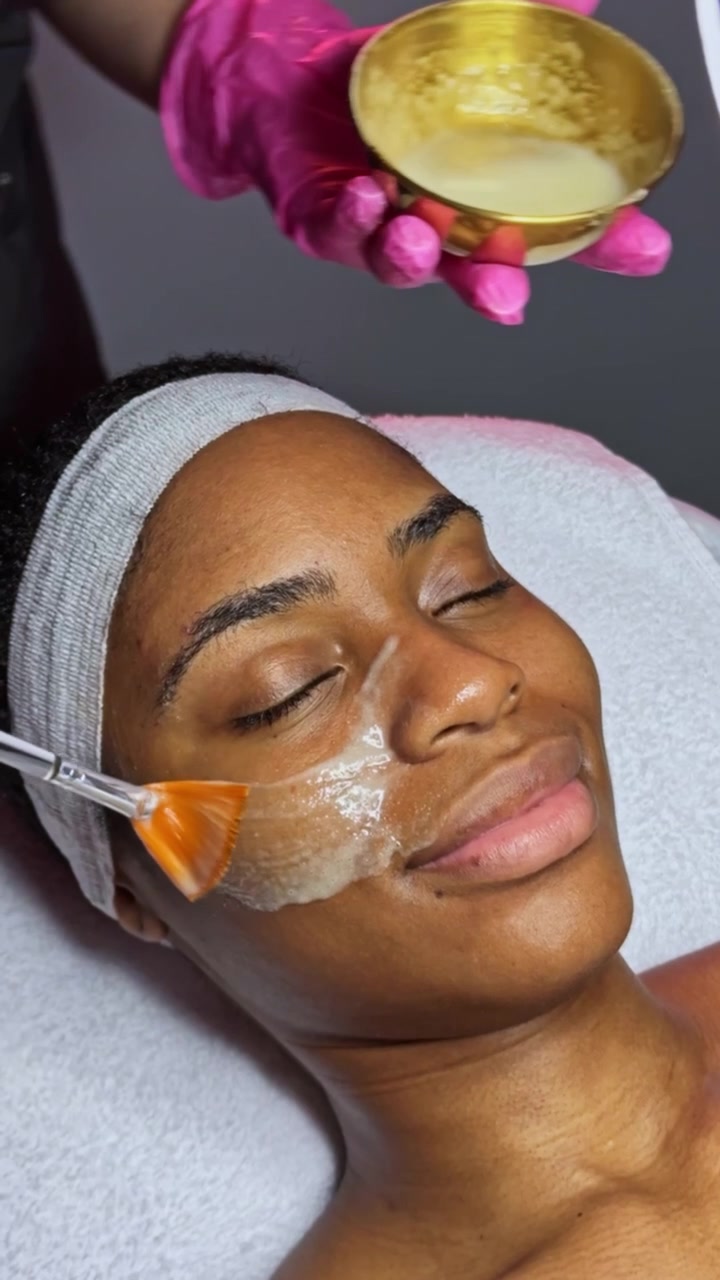 Cliente riceve un trattamento viso con una maschera applicata con un pennello in un centro estetico durante una seduta di skincare