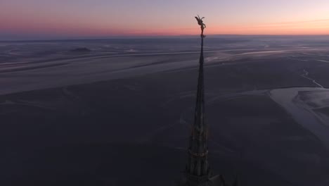 statue on top of abbey spire and amazing view of bay at sunset, mont saint-michel in normandy, france