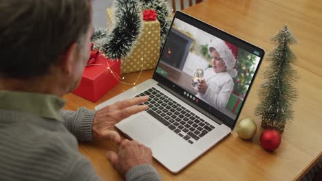 Happy-caucasian-senior-man-on-video-call-with-grandson-at-christmas-time