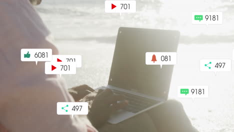animación de iconos de notificación con números sobre mujer afroamericana usando computadora portátil en la playa