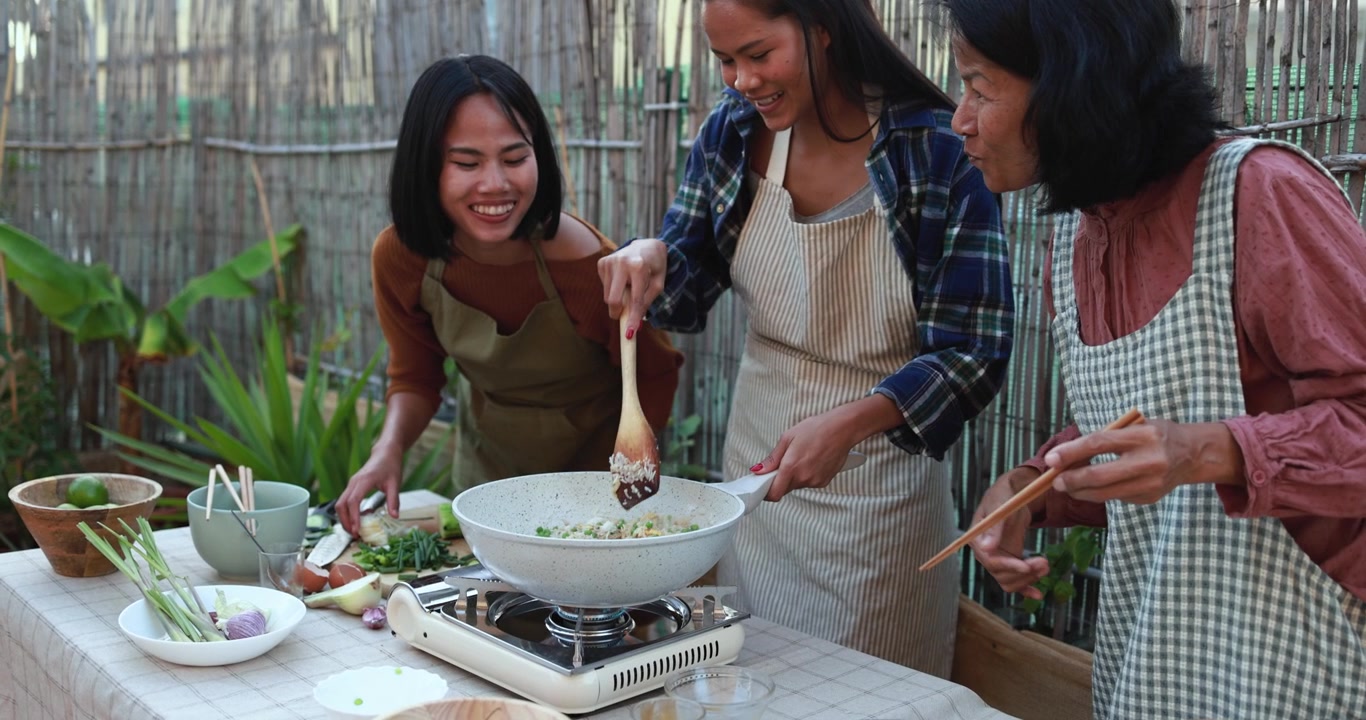 屋外キッチンで一緒に料理する3人のアジア人女性