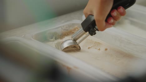 primer plano de la mano sosteniendo una cuchara de hielo, haciendo una bola de helado, golosina congelada