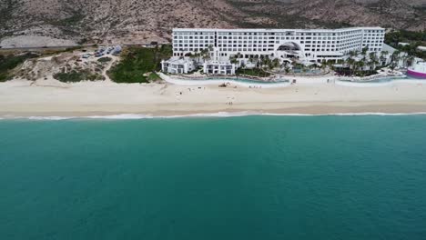 Vista-Panorámica-Aérea-De-La-Hermosa-Costa-Costera-De-Los-Cabos-Con-Vistas-A-La-Playa-De-Arena,-Una-Concurrida-Carretera-Costera-Y-El-Mar-Turquesa-Y-El-Renombrado-Hotel-Marquis-Durante-Unas-Vacaciones-En-México