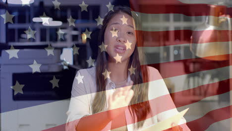 animation of flag of usa over happy biracial businesswoman talking