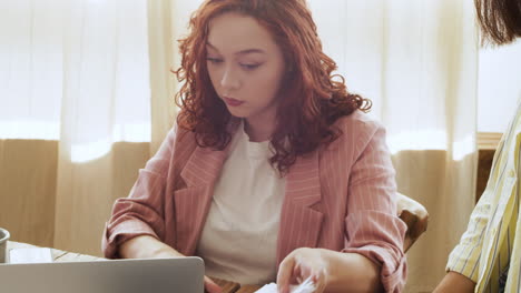 young woman sitting at table and tearing paper during a team meeting