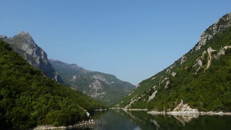 beautiful valley of koman lake in albania, high mountain peaks reflecting on calm water