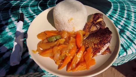 spicy fish yassa delicious african dish plate on table with green tye-dye table sheet close-up view