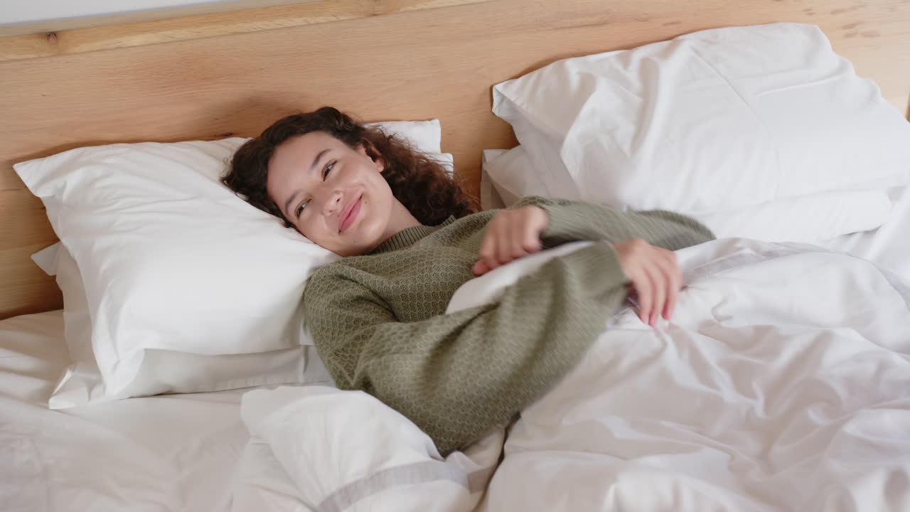 Relaxing in bed, woman smiling and enjoying cozy morning under blankets