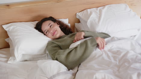 relaxing in bed, woman smiling and enjoying cozy morning under blankets