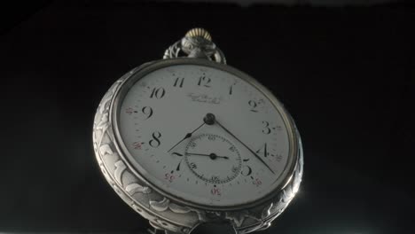 close-up of a vintage silver pocket watch with white face and black numbers