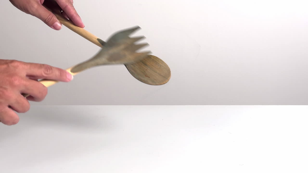 Hands Clanking Wooden Salad Servers Together on White Background