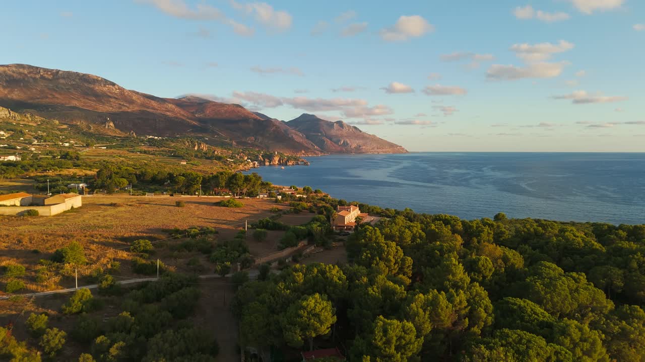 Push-in aerial drone shot over the Sicilian coast in Sicily, Italy during golden sunrise, showing cliffs, ocean, and natural scenery