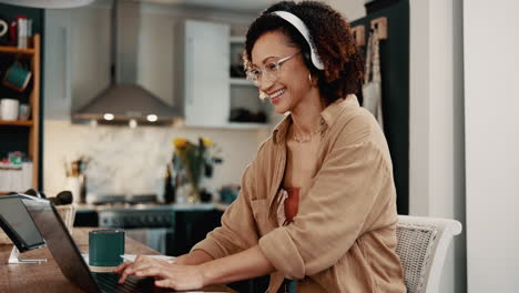 smiling woman working from home on her laptop with headphones on