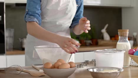 mujer tamizando harina en la cocina